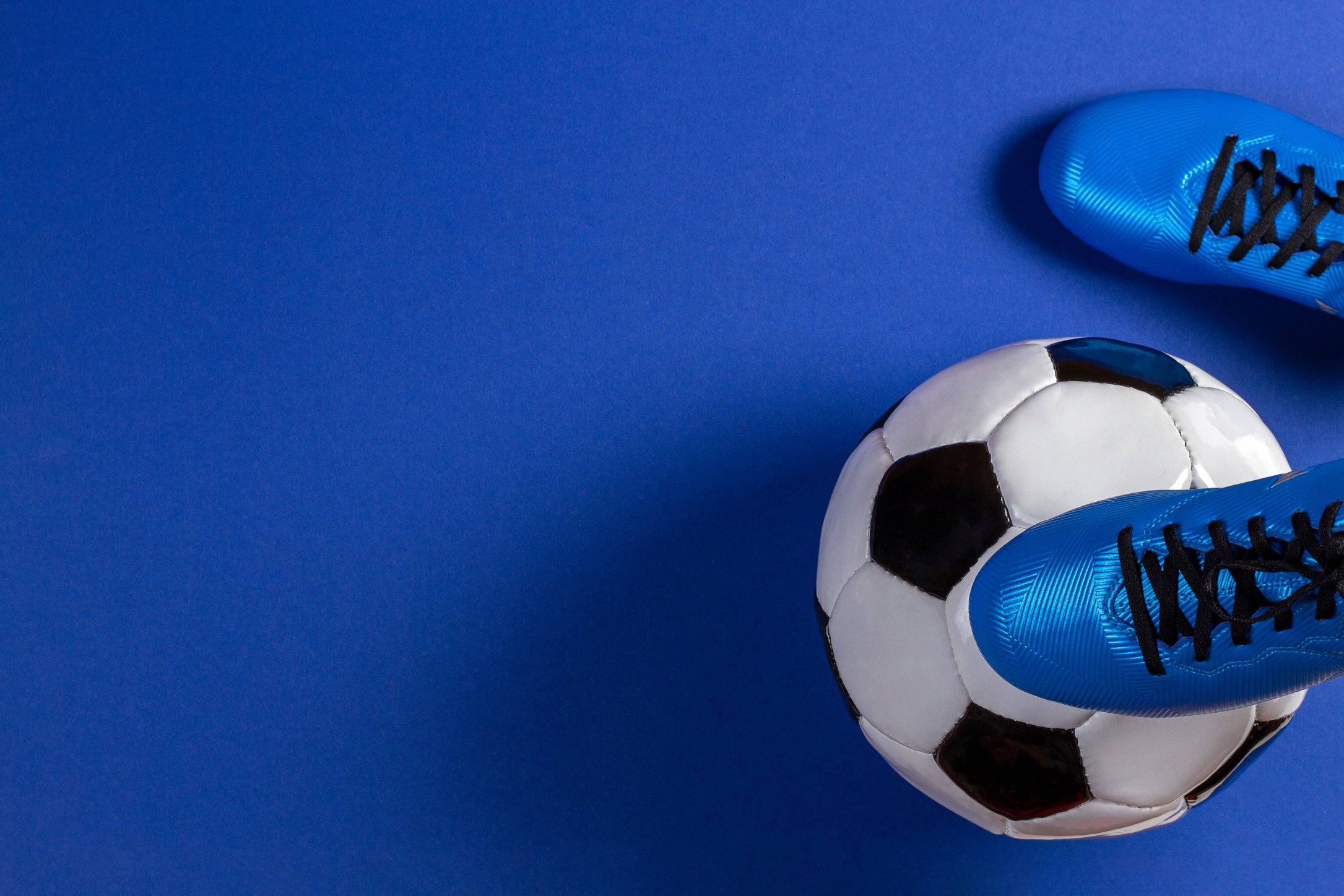 Soccer ball under soccer players feet on blue background