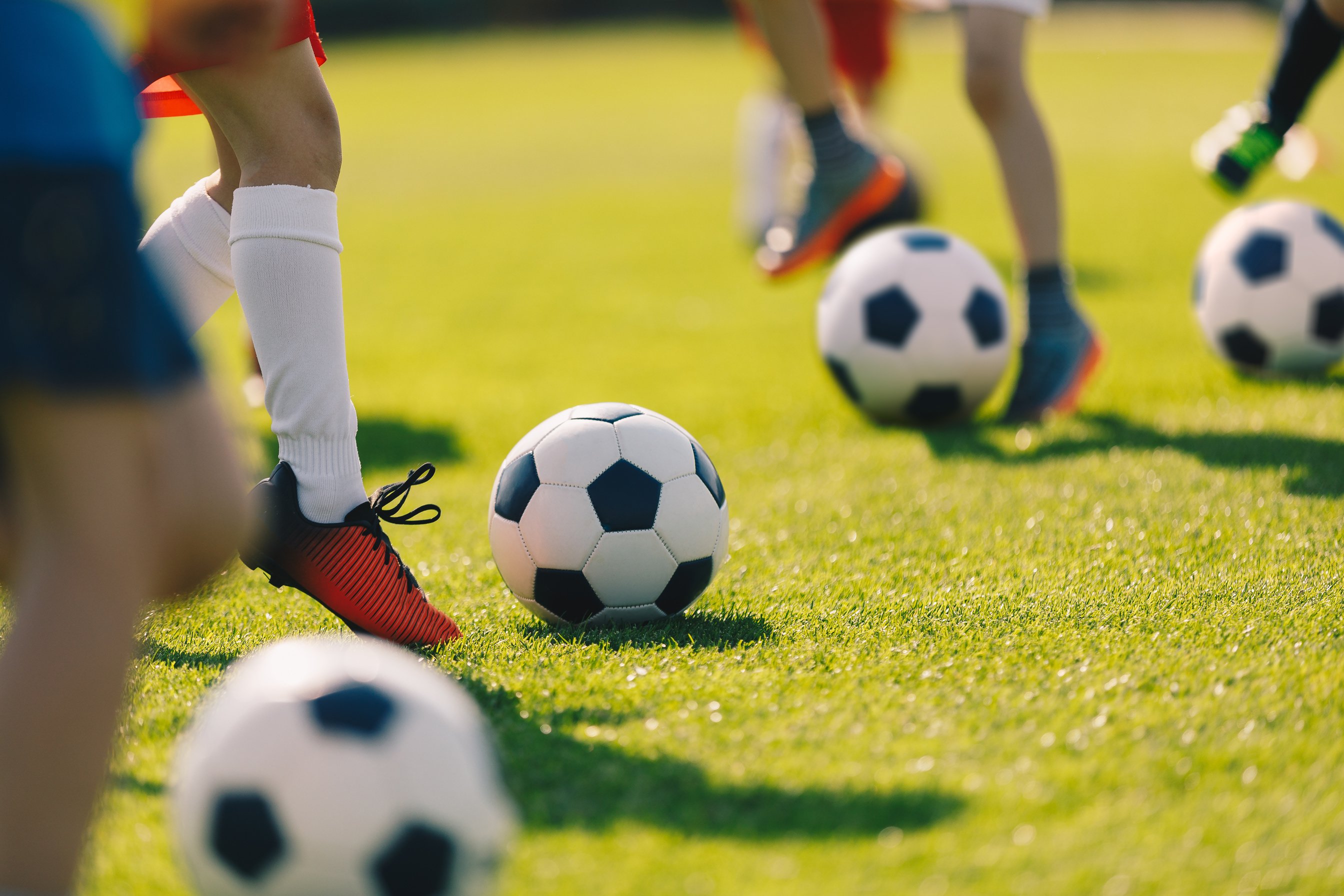 Soccer Football Training for Children. Kids Playing Soccer on Training Football Pitch. Beginner Soccer Drills for Kids. Coach in the Background Coaching Youth Soccer